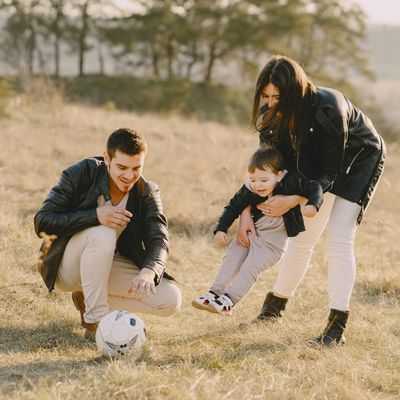 Pain-free family, who have received Next Level Chiropractic care, outdoors during the autumn playing with a soccer ball